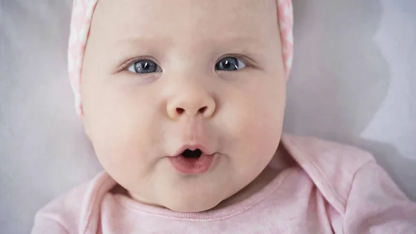 Top view of surprised baby looking at camera while lying in bed — Stock Photo