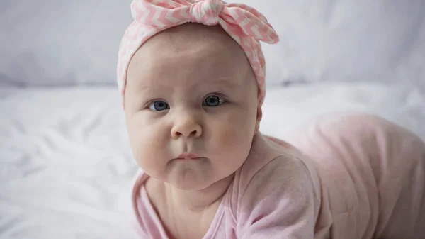 Curioso neonato in fascia con fiocco guardando la macchina fotografica — Foto stock