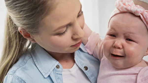 Mother holding crying baby girl in arms — Stock Photo