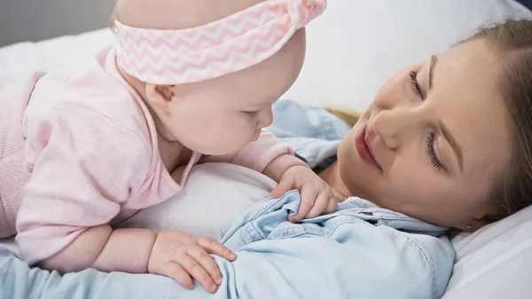 Sorridente madre sdraiata con neonata — Foto stock