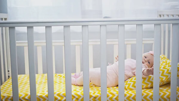 Infant girl lying in baby crib at home — Stock Photo