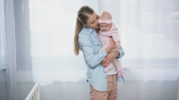 Donna in braccio figlia neonata in fascia con fiocco — Foto stock