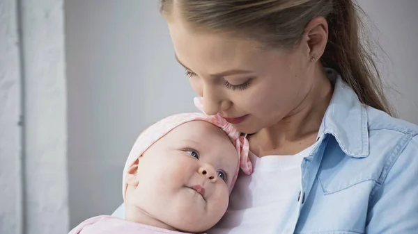 Femme regardant bébé fille dans bandeau avec arc — Photo de stock