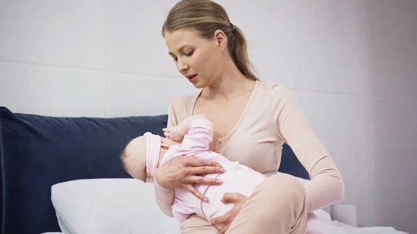 Woman holding in arms and breastfeeding baby at home — Stock Photo