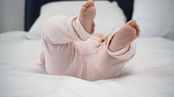 Vista ritagliata del bambino a piedi nudi sdraiato sul letto — Foto stock