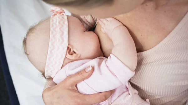 Mother feeding with breast baby girl in headband with bow — Stock Photo