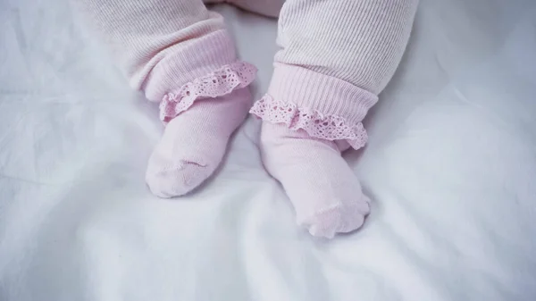 Vista ritagliata del bambino in pagliaccetto e calzini a letto — Foto stock