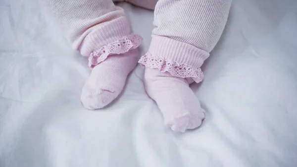 Cropped view of baby in romper and socks in bed — Stock Photo