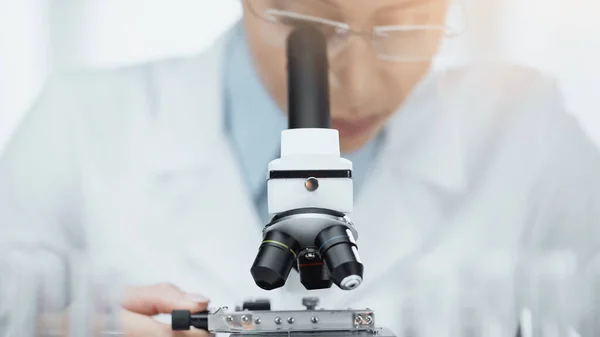 Blurred african american scientist looking through microscope — Stock Photo