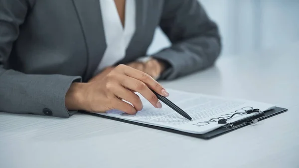 Обрезанный вид предпринимательницы, указывающей ручкой на контракт — стоковое фото