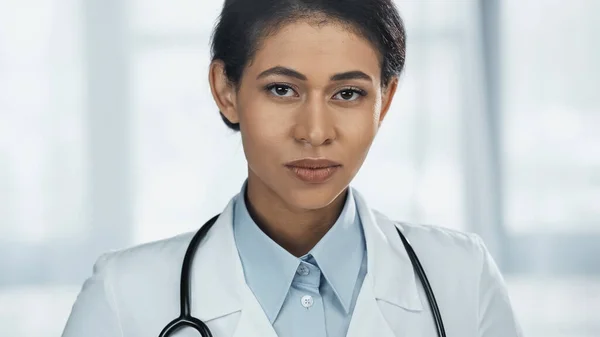 Giovane medico afroamericano in camice bianco con stetoscopio guardando la macchina fotografica — Foto stock