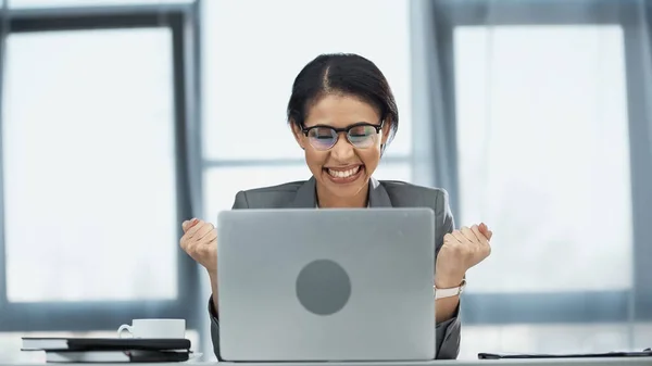 Excitada mulher de negócios afro-americana em óculos olhando para laptop — Fotografia de Stock