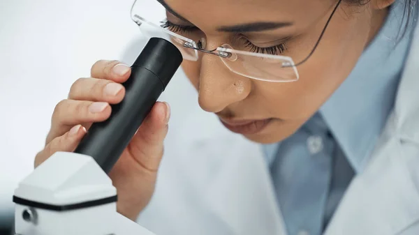 African american scientist in glasses looking through microscope — Stock Photo