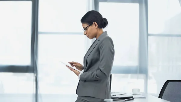 Mujer de negocios afroamericana utilizando tableta digital en la oficina - foto de stock