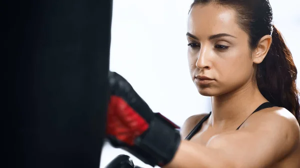 Entraînement ciblé de sportive avec sac de boxe dans la salle de gym — Photo de stock