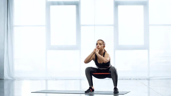 Junge brünette Frau trainiert mit Widerstandsband im Fitnessstudio — Stockfoto