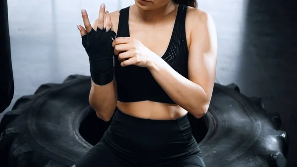 Vista recortada de la joven deportista poniéndose las manos vendajes de boxeo - foto de stock