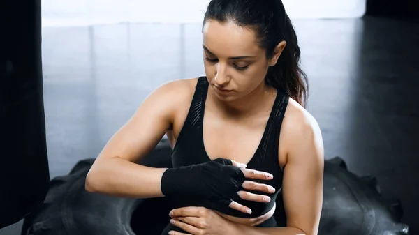 Joven morena deportista poniendo en las manos vendajes de boxeo - foto de stock