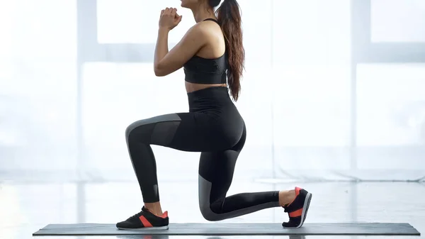 Cropped view of sportive woman working out on fitness mat in sports center — Stock Photo