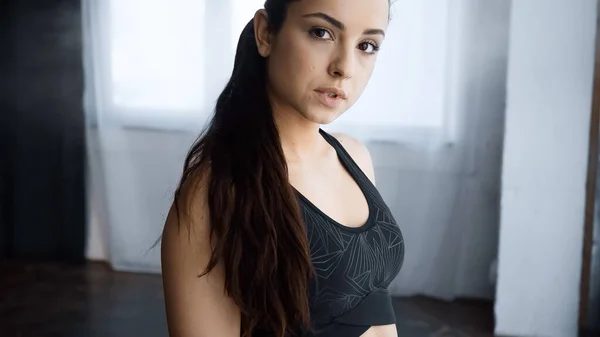 Deportivo joven mujer en crop top mirando la cámara en el gimnasio - foto de stock