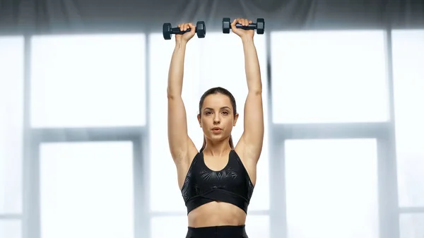 Strong sportswoman in crop top exercising with dumbbells — Stock Photo
