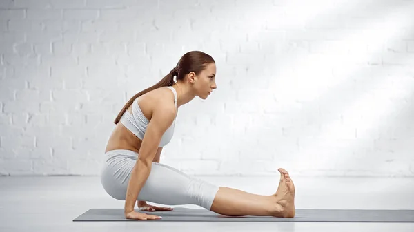 Side view of young woman practicing yoga on floor — Stock Photo