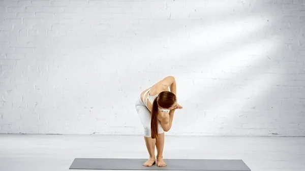 Bruna donna in piedi in sedia torsione yoga posa — Foto stock