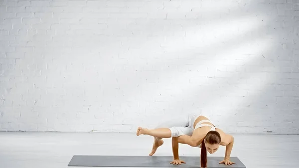 Sportiva a piedi nudi in piedi su mani su tappetino yoga — Foto stock