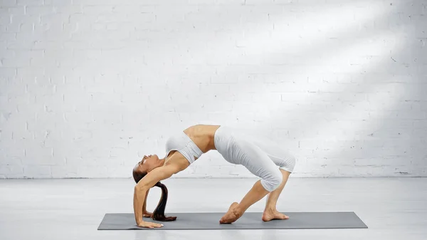 Side view of pretty woman bending back on yoga mat — Stock Photo