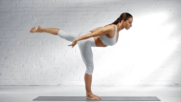 Side view of barefoot woman in warrior pose practicing yoga at home — Stock Photo