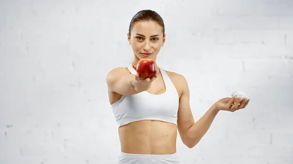 Sportswoman holding marshmallow and blurred apple — Stock Photo