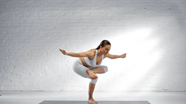 Mujer balanceándose en una pierna mientras practica yoga - foto de stock