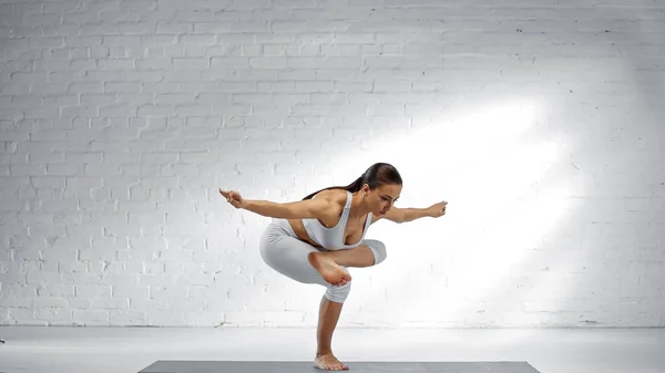 Adatto donna bilanciamento su una gamba, mentre facendo posa yoga — Foto stock