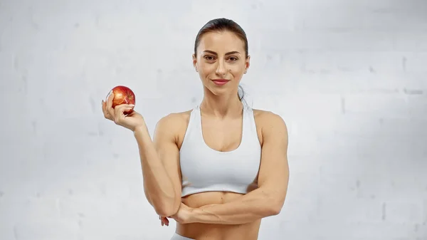 Улыбающаяся спортсменка держит органическое яблоко — стоковое фото