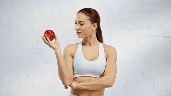 Sportswoman en haut de sport blanc regardant pomme mûre — Photo de stock
