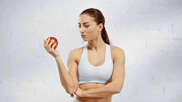 Apto esportista olhando para maçã fresca em casa — Fotografia de Stock
