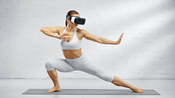 Ajuste mujer usando auriculares de realidad virtual en estera de yoga - foto de stock