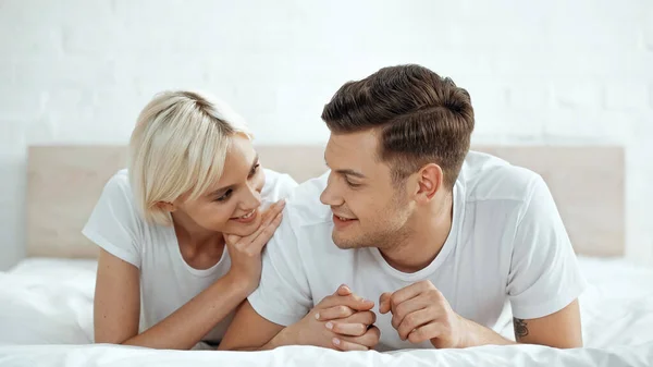 Fröhlicher Mann hält Hand in Hand mit fröhlicher Frau im Bett — Stockfoto