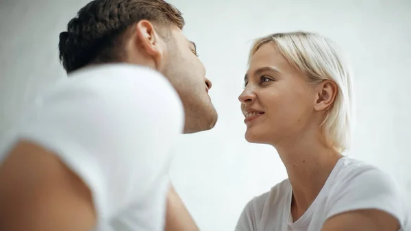 Mujer rubia sonriendo mientras mira novio feliz - foto de stock