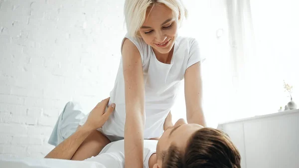 Happy young woman looking at man lying on bed — Stock Photo