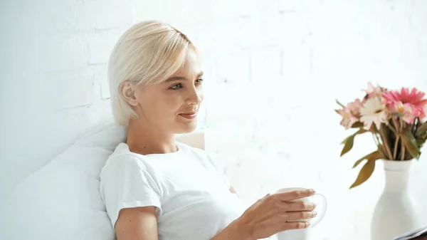 Freudige junge Frau mit einer Tasse Kaffee zu Hause — Stockfoto