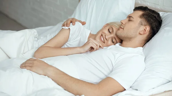 Mulher loira feliz descansando na cama com namorado — Fotografia de Stock