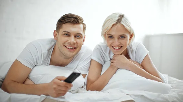 Alegre casal sorrindo enquanto assiste filme no quarto — Fotografia de Stock