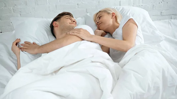Jovem mulher e homem deitado na cama e olhando um para o outro — Fotografia de Stock