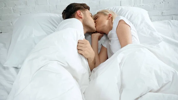 Joven mujer y hombre besándose en la cama - foto de stock