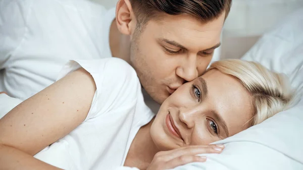 Young man kissing cheek of joyful girlfriend — Stock Photo