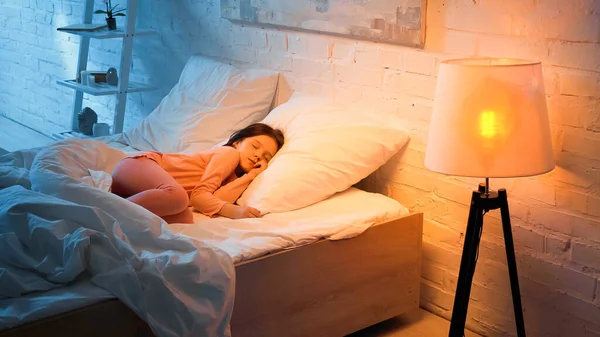 Chica preadolescente durmiendo en la cama durante la noche - foto de stock