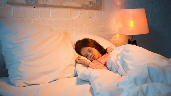 Niño preadolescente durmiendo en la cama durante la noche - foto de stock