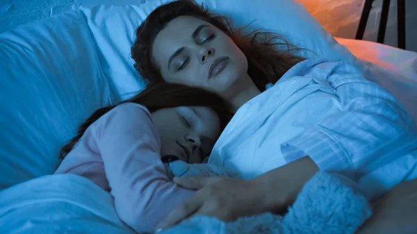 Woman hugging child while sleeping during night — Stock Photo