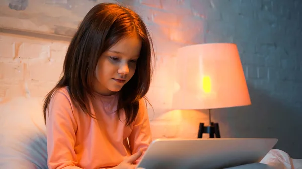 Preteen girl using blurred laptop on bed — Stock Photo